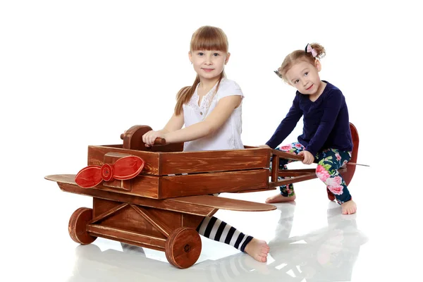 两个姐妹在一架木飞机上玩耍 — 图库照片