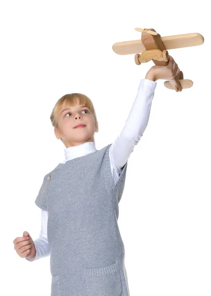 Little girl is playing with a wooden plane. — Stock Photo, Image
