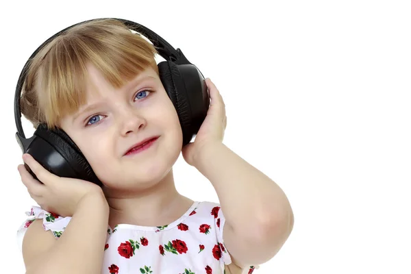 Une petite fille avec écouteurs écoutant de la musique. — Photo