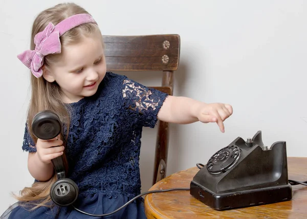 Mała dziewczynka dzwoni do starego telefonu.. — Zdjęcie stockowe