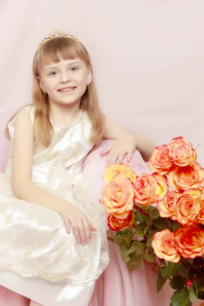 Menina senta-se ao lado de um buquê de flores . — Fotografia de Stock