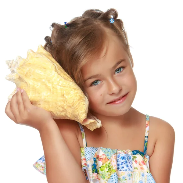 Little girl in a swimsuit with a seashell — Stock Photo, Image