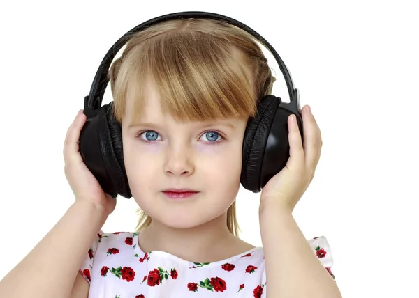 A little girl with headphones listening to music. — Stock Photo, Image