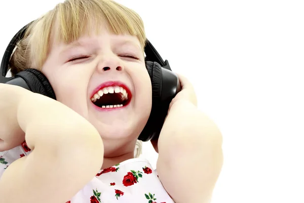 Una niña con auriculares escuchando música. —  Fotos de Stock