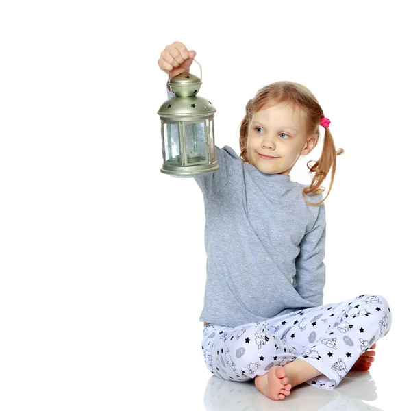 En liten flicka håller en lampa. — Stockfoto