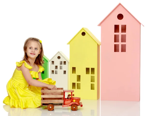 Little girl is playing with a wooden car. — Stock Photo, Image