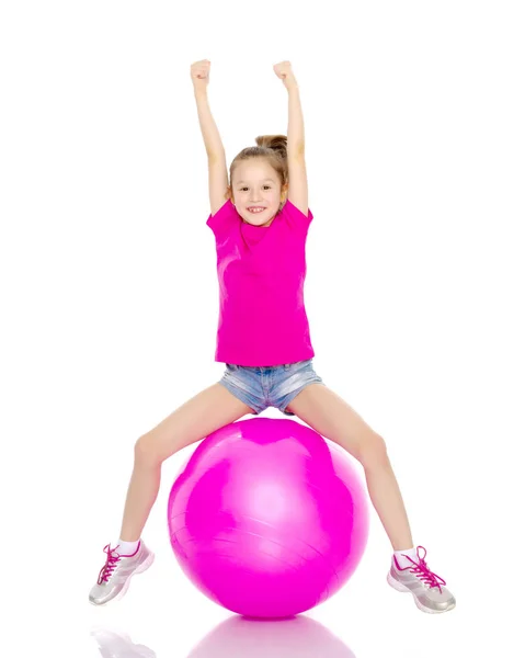 小さな女の子が大きなジム ボールにジャンプして. — ストック写真