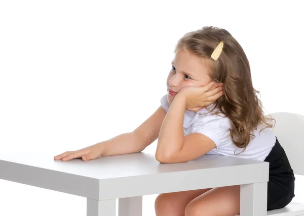 La niña está sentada en la mesa. —  Fotos de Stock