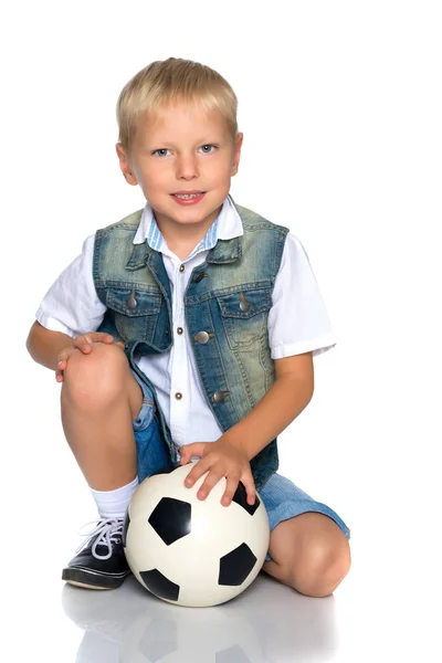 Menino está jogando com uma bola de futebol . — Fotografia de Stock