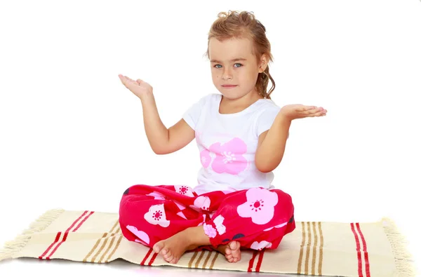 Liten flicka mediterar på mattan. — Stockfoto
