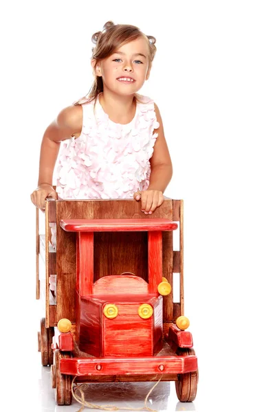 Menina está brincando com um carro de madeira . — Fotografia de Stock