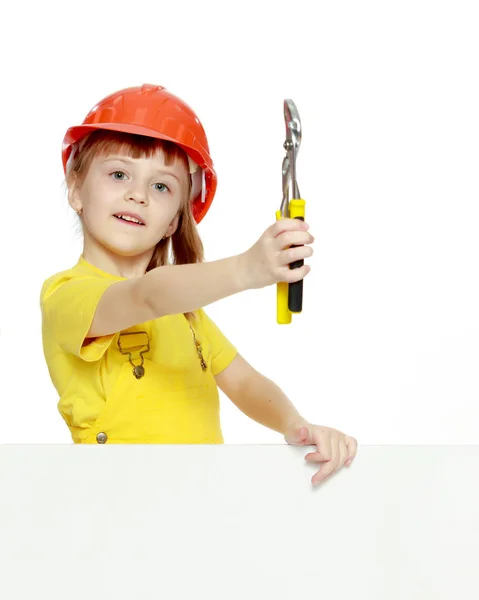 Chica en un casco de construcción asoma por detrás de una valla publicitaria . —  Fotos de Stock