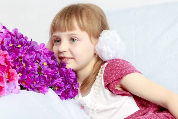 Fille s'assoit à côté d'un bouquet de fleurs . — Photo