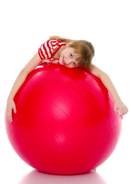Klein meisje doet oefeningen op een grote bal voor fitness. — Stockfoto