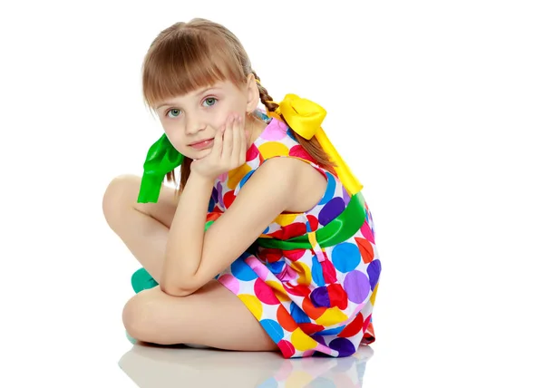 Ein kleines Mädchen in einem Kleid mit einem Muster aus buntem Zirkel — Stockfoto