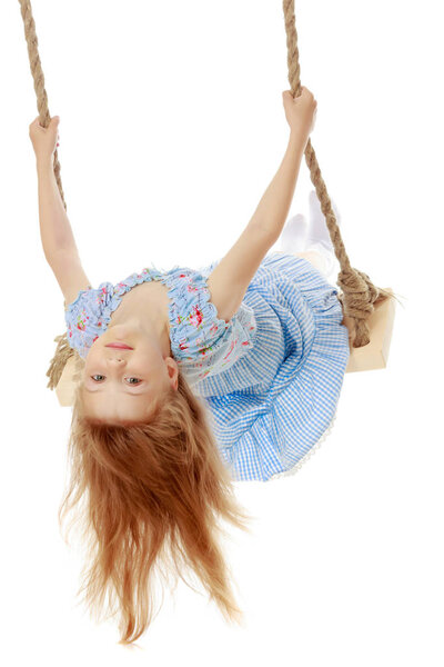 Маленькая девочка качается на качелях