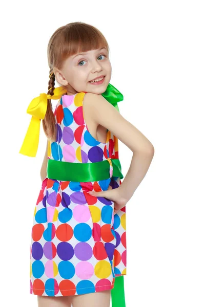 Маленькая девочка в платье с рисунком из разноцветного цирка — стоковое фото