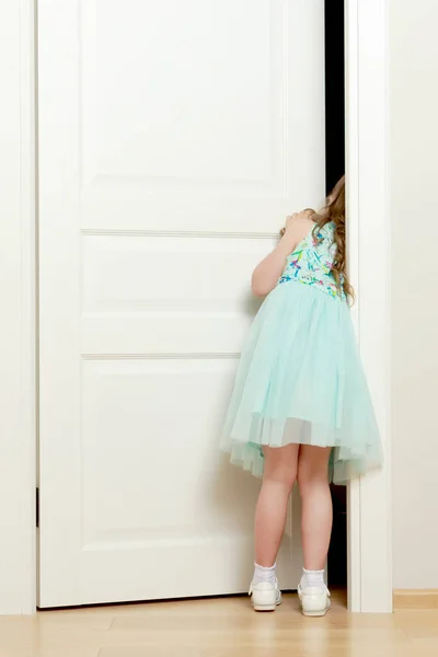 Une petite fille se tient près de la porte . — Photo