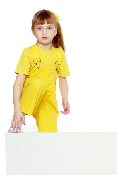 Girl with a short bangs on her head and bright yellow overalls. — Stock Photo, Image