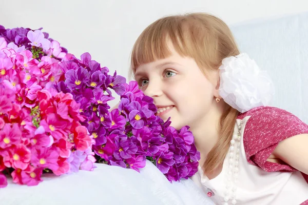 Ragazza si siede accanto a un mazzo di fiori . — Foto Stock