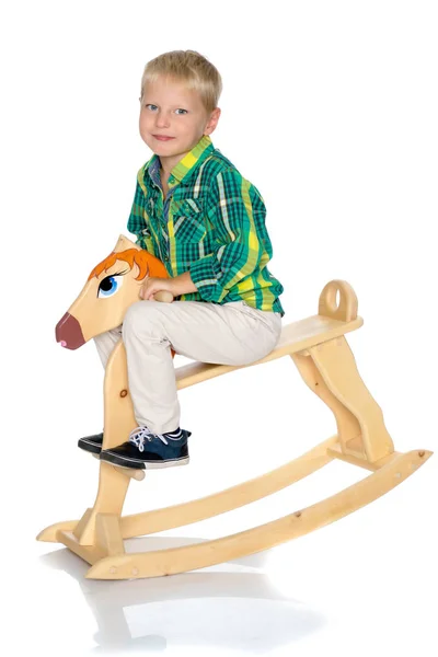 A little boy is riding a wooden horse — Stock Photo, Image