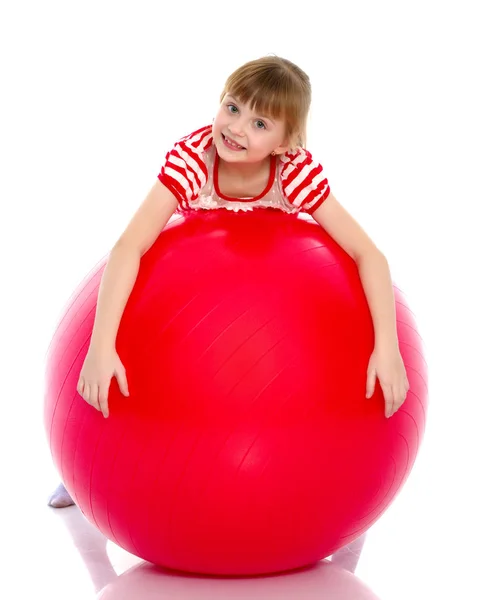 Klein meisje doet oefeningen op een grote bal voor fitness. — Stockfoto