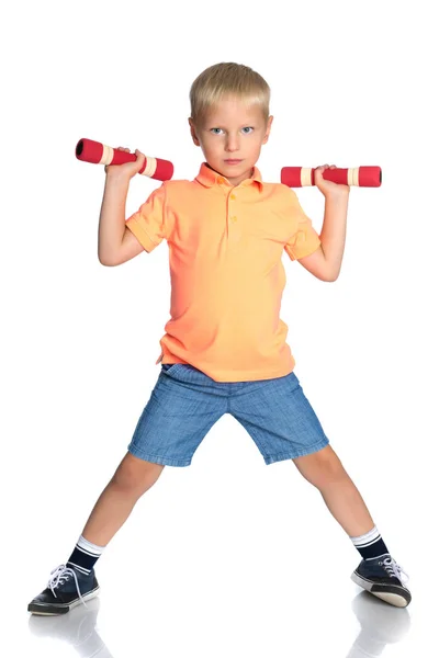 Een kleine jongen is het opheffen van halters. — Stockfoto