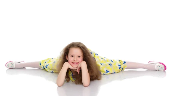 Den lilla gymnasten utför ett akrobatiskt element på golvet. — Stockfoto