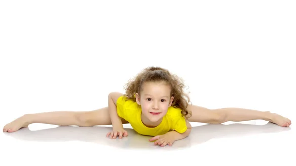 Den lilla gymnasten utför ett akrobatiskt element på golvet. — Stockfoto