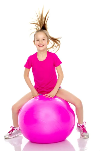 Una niña está saltando en la gran pelota de gimnasia . — Foto de Stock