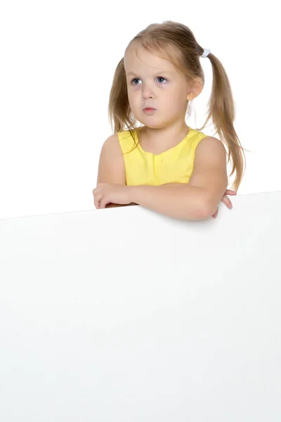 Маленькая девочка смотрит из-за пустого плаката. — стоковое фото