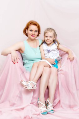 Anne ve kızı koltukta oturuyor.