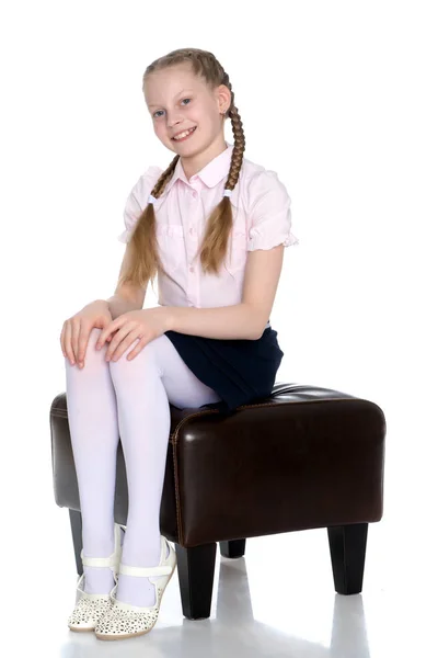 Дівчина школярка з довгими кісками сидить на дивані . — стокове фото