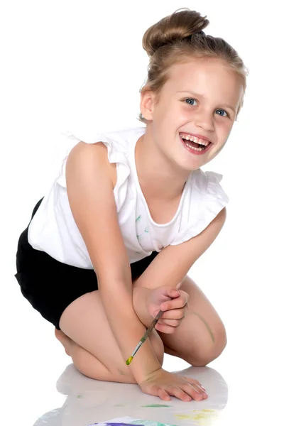 Uma menina pinta com tinta e pincel . — Fotografia de Stock