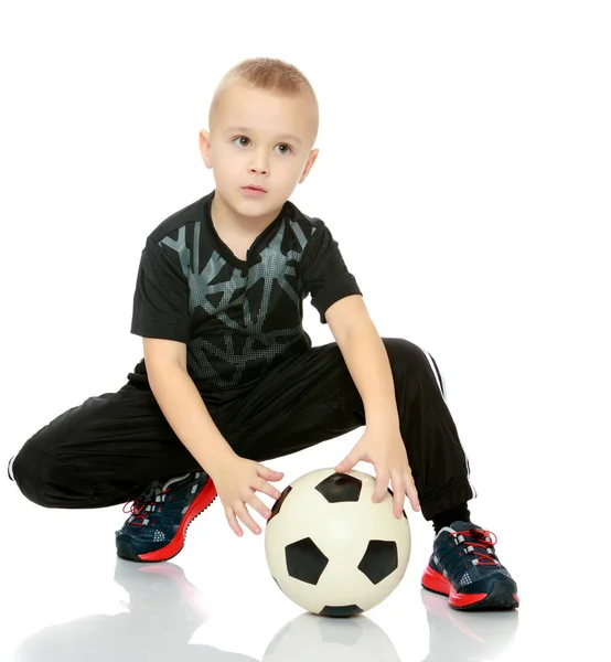 Menino está jogando com uma bola de futebol . — Fotografia de Stock