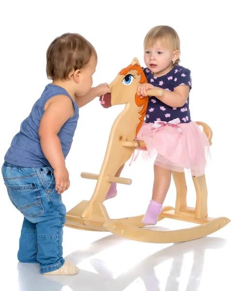 Niño y niña jugando con un caballo de madera . —  Fotos de Stock