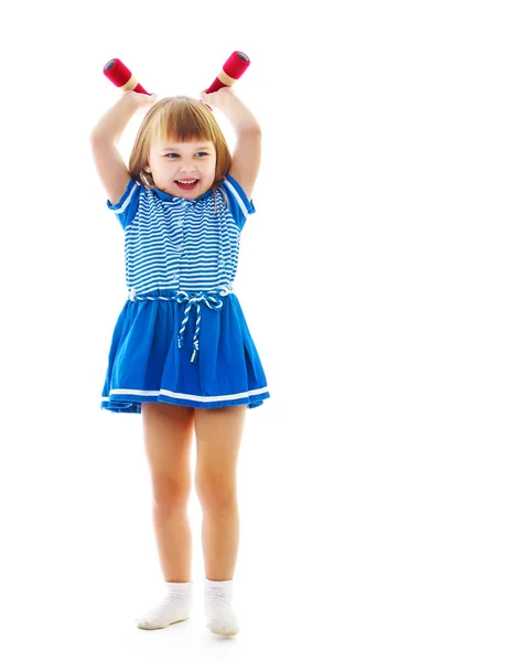 Маленькая девочка делает упражнения с гантелями. — стоковое фото