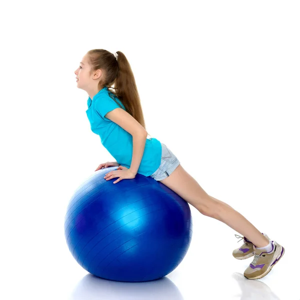 Holčička dělá cvičení na velký míč pro fitness. — Stock fotografie