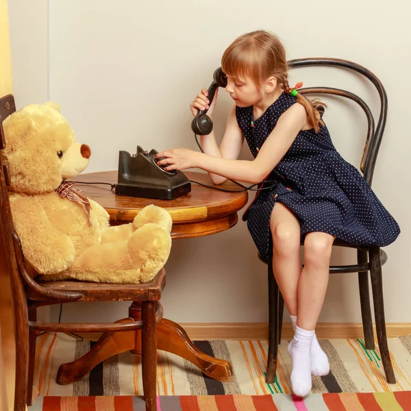 Een klein meisje belt op de oude telefoon.. — Stockfoto
