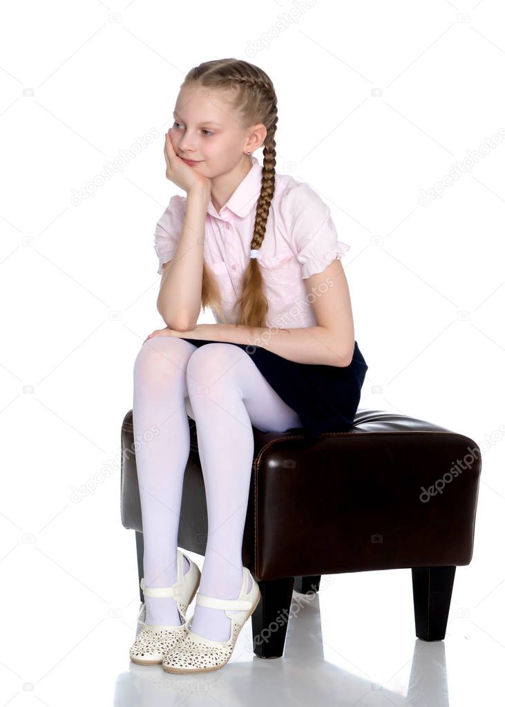 Girl schoolgirl with long pigtails sitting on the couch.
