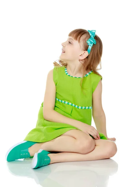 The girl is sitting on the floor with her hands clasped around h — Stock Photo, Image