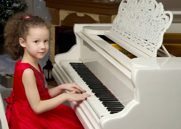 Piękna dziewczynka gra na białym fortepianie. — Zdjęcie stockowe
