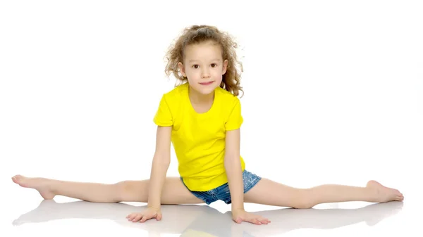 Den lilla gymnasten utför ett akrobatiskt element på golvet. — Stockfoto