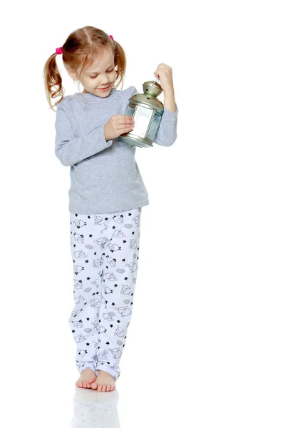 Een klein meisje houdt een lamp. — Stockfoto