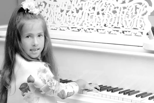 漂亮的小女孩正在用一架白色的大钢琴弹奏. — 图库照片