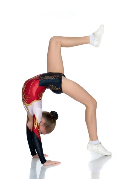 Gymnasten utför en bro med en upphöjd ben. — Stockfoto