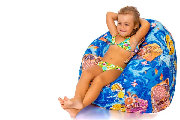 La bambina in costume da bagno è seduta su un cuscino . — Foto Stock