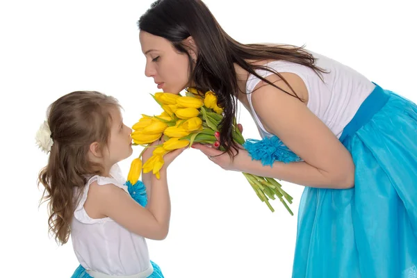 Mãe e filha cheirando tulipas amarelas . — Fotografia de Stock