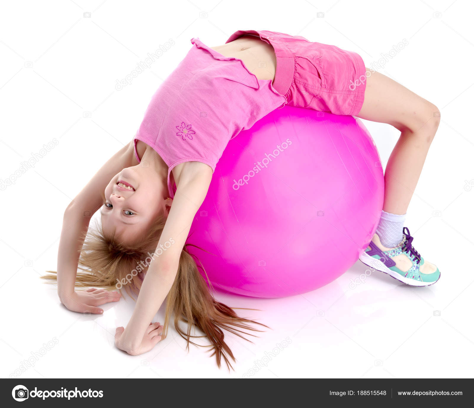 Little girl doing exercises on a big ball for fitness. Stock Photo by