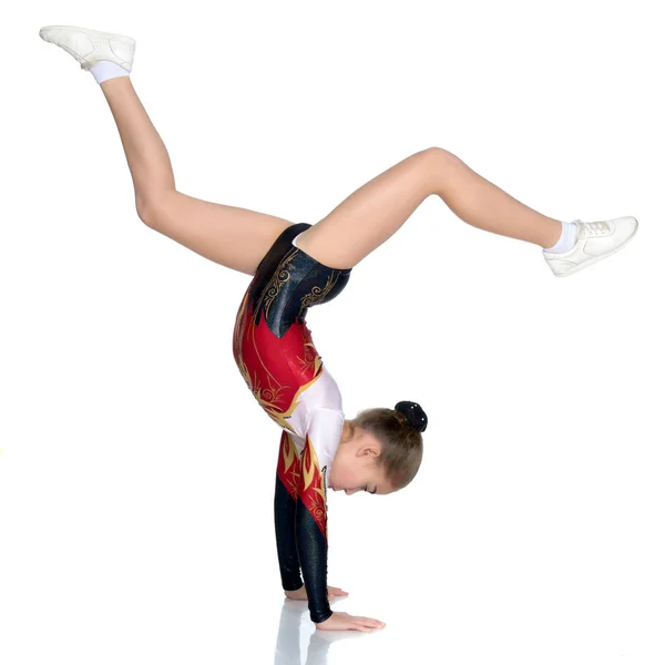 Gymnastka provádí stojan s ohnutýma nohama. — Stock fotografie